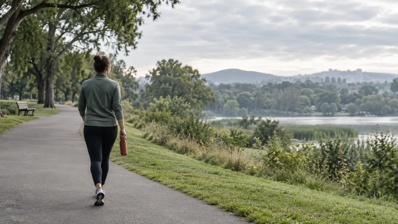 An adult walking on a quiet park path, seen from behind